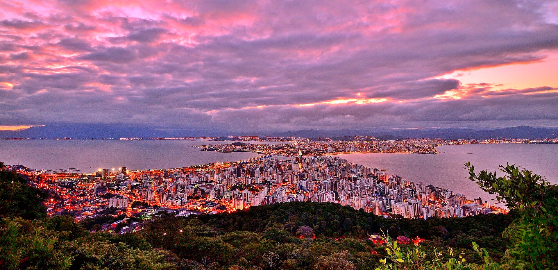 Sunset over Florianópolis from Morro da Cruz, the island skyline stretching toward the bridge.