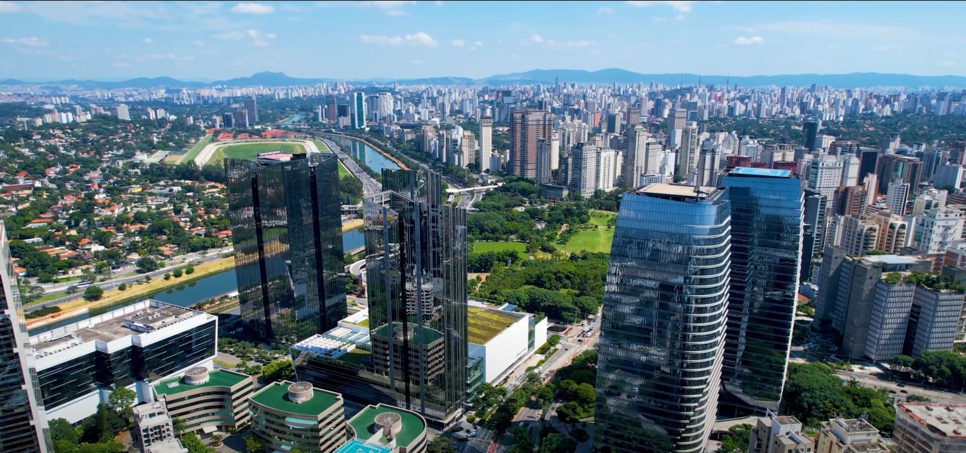 São Paulo skyline along Marginal Pinheiros with the Corporate Towers and Pico do Jaraguá in the distance.